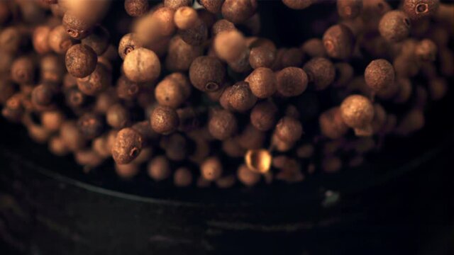 Super slow movement from the mortar fall out of the peas of black pepper. Filmed on a high-speed camera at 1000 fps. Against a dark background. High quality FullHD footage