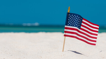 American Flag on the Beach. 4th of July Independence Day. US starry striped patriotic symbol. United States Holidays. Summer vacations. Ocean sand. Bright sunny day and blue color of sea salt water.  - Powered by Adobe