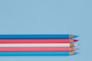 Colored pencils on light blue background. Pastel pink, blue, white colors. Top view - obrazy, fototapety, plakaty