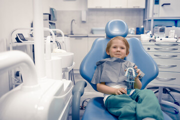 Caucasian child kid sit in dental chair at dentist doctor. Preschooler treating teeth, happy. Advertising concept.