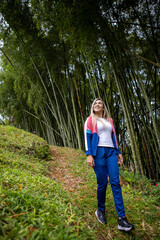 Vertical shot of a Hispanic woman with blonde hair posing on a forest background