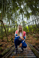 Vertical shot of a Hispanic woman with blonde hair posing on a forest background