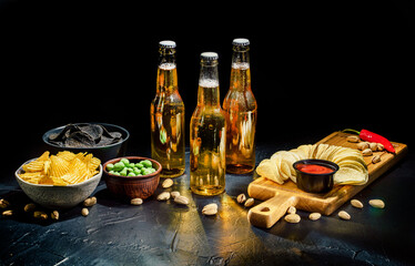 Cold beer with potato chips, snacks and sauce on dark background - Powered by Adobe