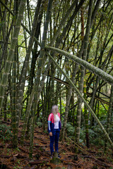 Vertical shot of a Hispanic woman with blonde hair on a forest background
