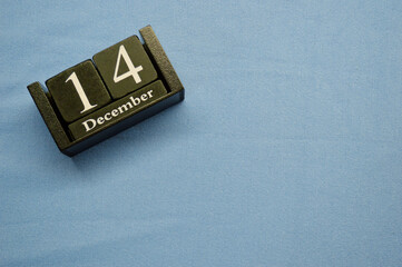 Wooden calendar from blocks on a blue background with copy space. December 14th