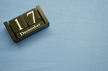 Wooden calendar from blocks on a blue background with copy space. December 17th