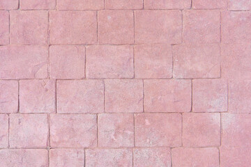 Front view of a wall of irregular shape tiles or slabs. Reddish textured background