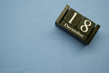 Wooden calendar from blocks on a blue background with copy space. December 18th