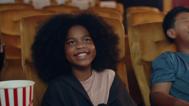 Attractive cheerful young black african girl laughing while watching film in movie theater. Lifestyle entertainment concept.