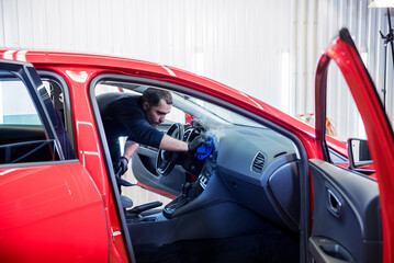 Car service worker cleans interiror with steam cleaner