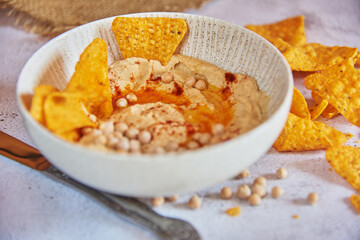 Chickpea hummus flavored with olive oil and sweet paprika and corn nachos.