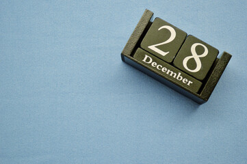 Wooden calendar from blocks on a blue background with copy space. December 28th