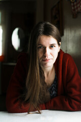 Portrait of young woman sitting at the table in the her house.