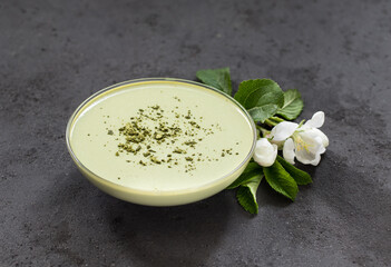 Creamy green matcha tea jelly in a glass bowl on a dark gray background