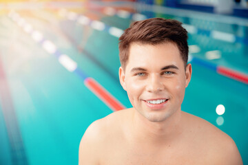 Portrait young man smiling on background of pool, concept of swimmer before training at school