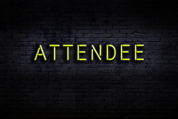 Night view of neon sign on brick wall with inscription attendee