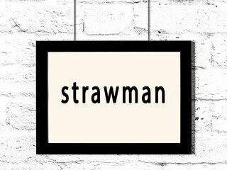 Black frame hanging on white brick wall with inscription strawman - obrazy, fototapety, plakaty