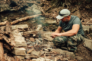 A man is making camp fire in the woods.