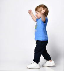 Side view of a child in a blue hoodie and wide pants, raised his hands to the top, the face is not visible