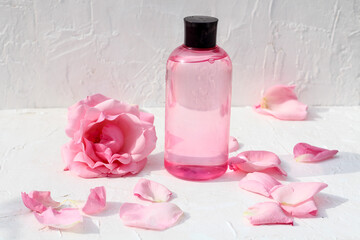 Fototapeta na wymiar face toner with pure rose extract. Composition is decorated with fresh rose petals