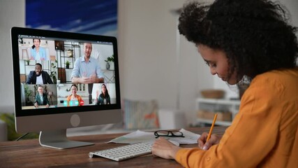 Distance learning, online lecture. African American smart girl, student or freelancer, listening and watching video conference webinar, takes notes, gaining knowledge,multiracial people at the screen