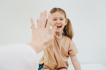 Cheerful little girl with two pony tails giving high five. smiling with her baby teeth, over white background