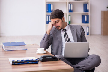 Young attractive male employee sitting at workplace