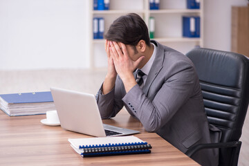 Young attractive male employee sitting at workplace