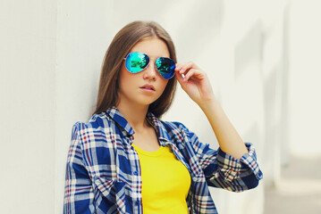 Fototapeta premium Portrait close up of beautiful young woman wearing a sunglasses posing in a city