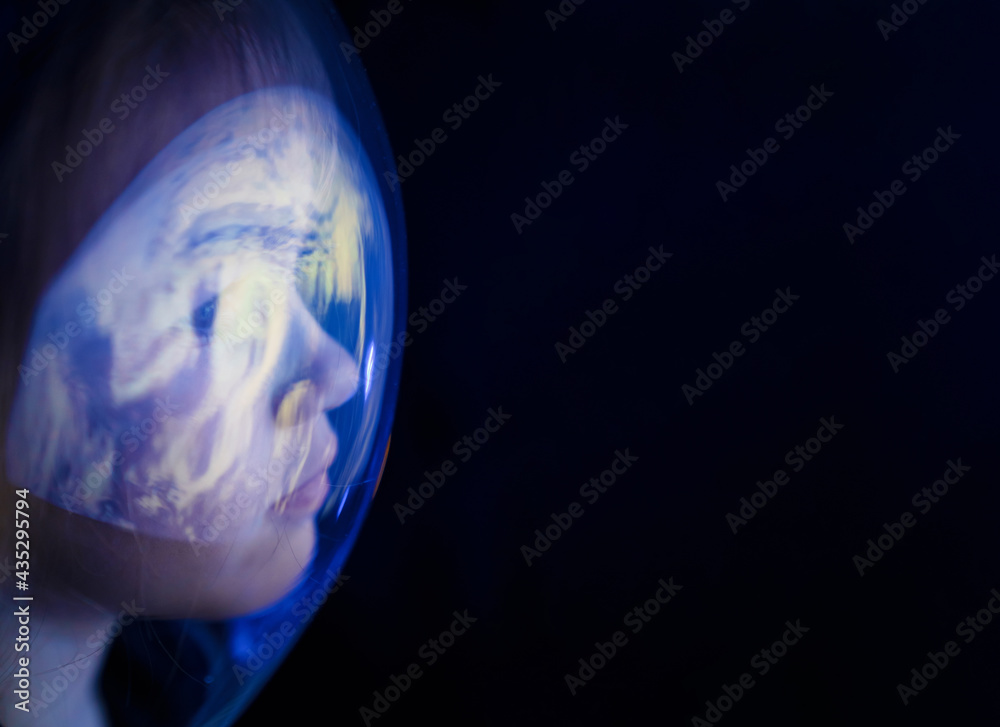Wall mural girl dreams of becoming astronaut and flying into space. reflection of planet