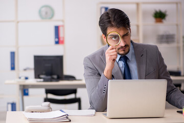 Young male employee auditor holding magnifying glass