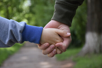 Child and adult holding hands. Only hands are visible in close-up