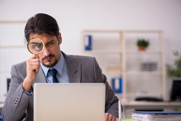 Young male employee auditor holding magnifying glass