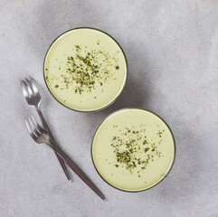 Italian dessert Panna Cotta green matcha tea in a glass bowl on a light gray background top view