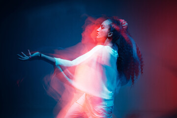 Colourful portrait of young mixed race girl dancing in studio. Long exposure. Colored neon light.