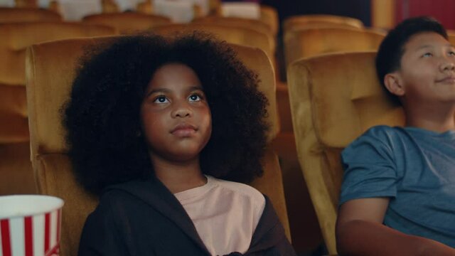 Attractive cheerful young black african girl laughing while watching film in movie theater. Lifestyle entertainment concept.
