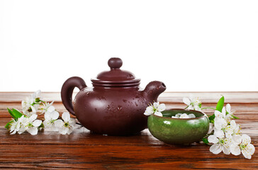 Obraz na płótnie Canvas Cup of green tea and clay teapot with cherry flowers isolated on a white background. Spring tea ceremony.