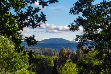 Fototapeta na wymiar Far mountain and sky with clouds seen among the trees