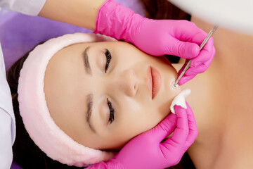 Cosmetologist at spa beauty salon doing acne treatment using mechanical instrument. Concept of medical treatment of rejuvenation and skincare.