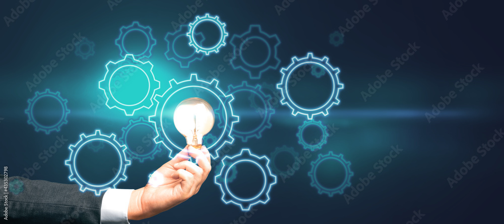 Poster start up and idea concept with digital gears and glowing light bulb in man hand on abstract dark bac