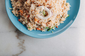 Thai style Squid Fried Rice served in blue ceramic dish on white table.