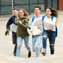 Fototapeta premium Group of teenagers running on city street and having fun