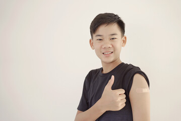 Mixed Asian teen boy givnig thumb up and showing his arm with bandage after got vaccinated or  inoculation - obrazy, fototapety, plakaty