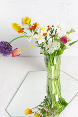 Garden flowers bouquet reflecting in mirror on white background