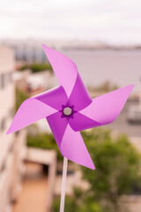 Purple pinwheel in the midday sun with trees and buildings