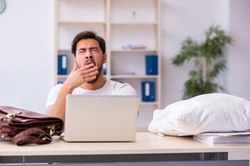 Young male employee coming to work straight from bed