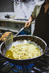 Vertical shot of a Hispanic woman cooking French fries in a bow