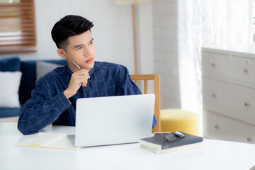 Fototapeta premium Young asian business man planning working and using laptop computer on desk at home, notes about finance, male study and learning, businessman thinking idea, business and communication concept.