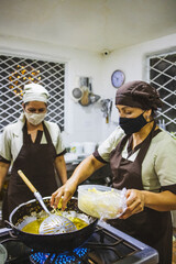 Vertical shot of two Hispanic women cooking chicken with mushroom sauce