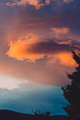 beautiful intense sunset sky with pink and golden tones over the mountains and trees